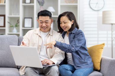 Asian couple smiling looking at a laptop